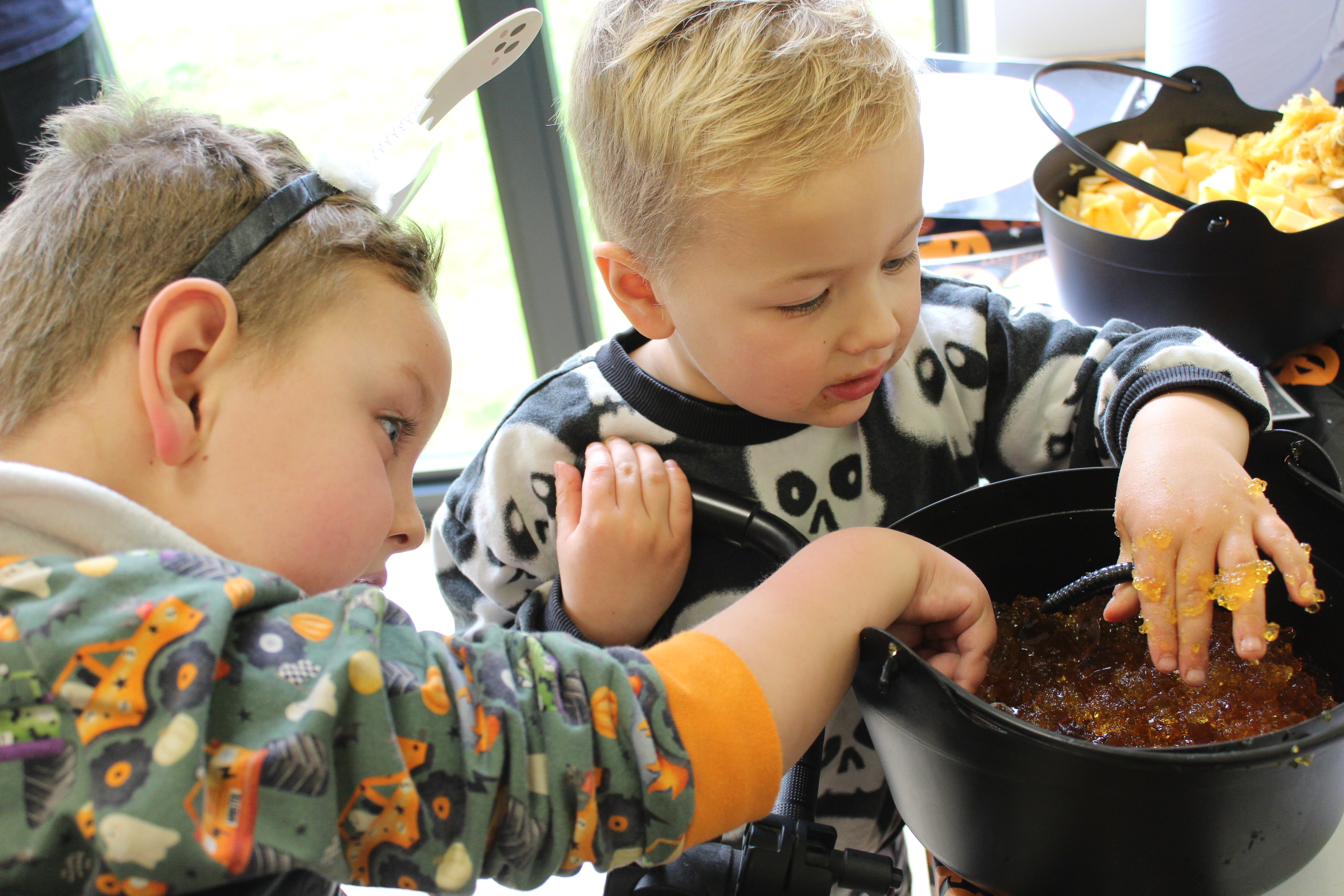 Two brothers dipping their hand into orange jelly at the East Sussex Pumpkin Party