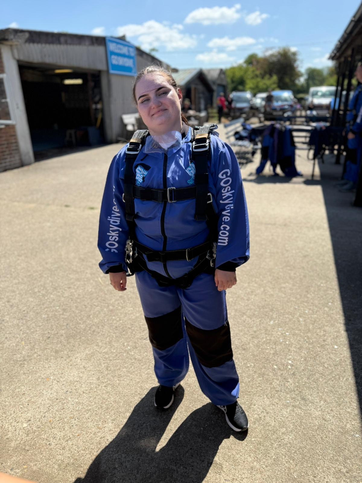 A women in a blue skydiving suit smiling towards the camera