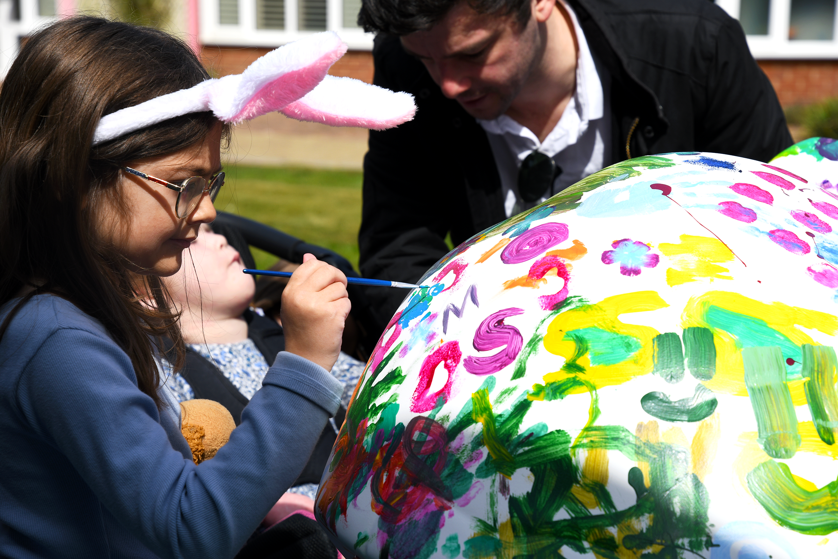 Child with family painting a sculpture in the garden at Demelza Kent
