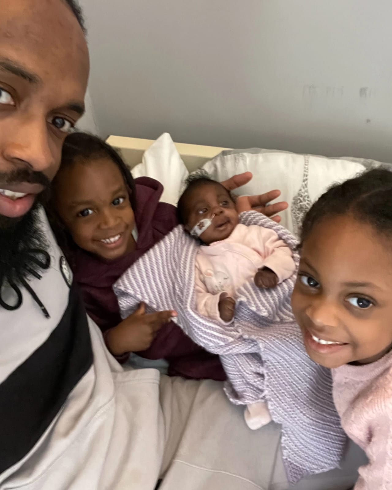 A older man, two younger girls and a baby girl holding a camera and smiling