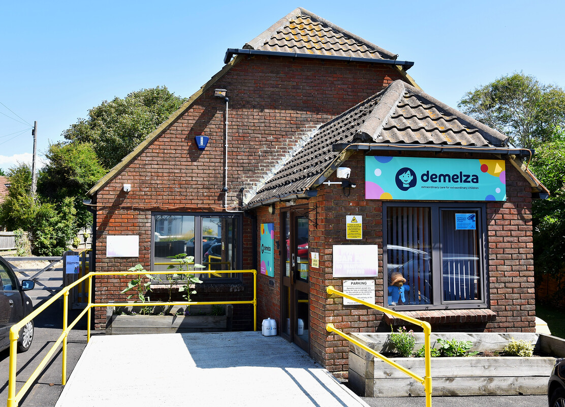 Entrance to Demelza East Sussex Community Hub with bright signage and accessible pathway, inviting visitors in.