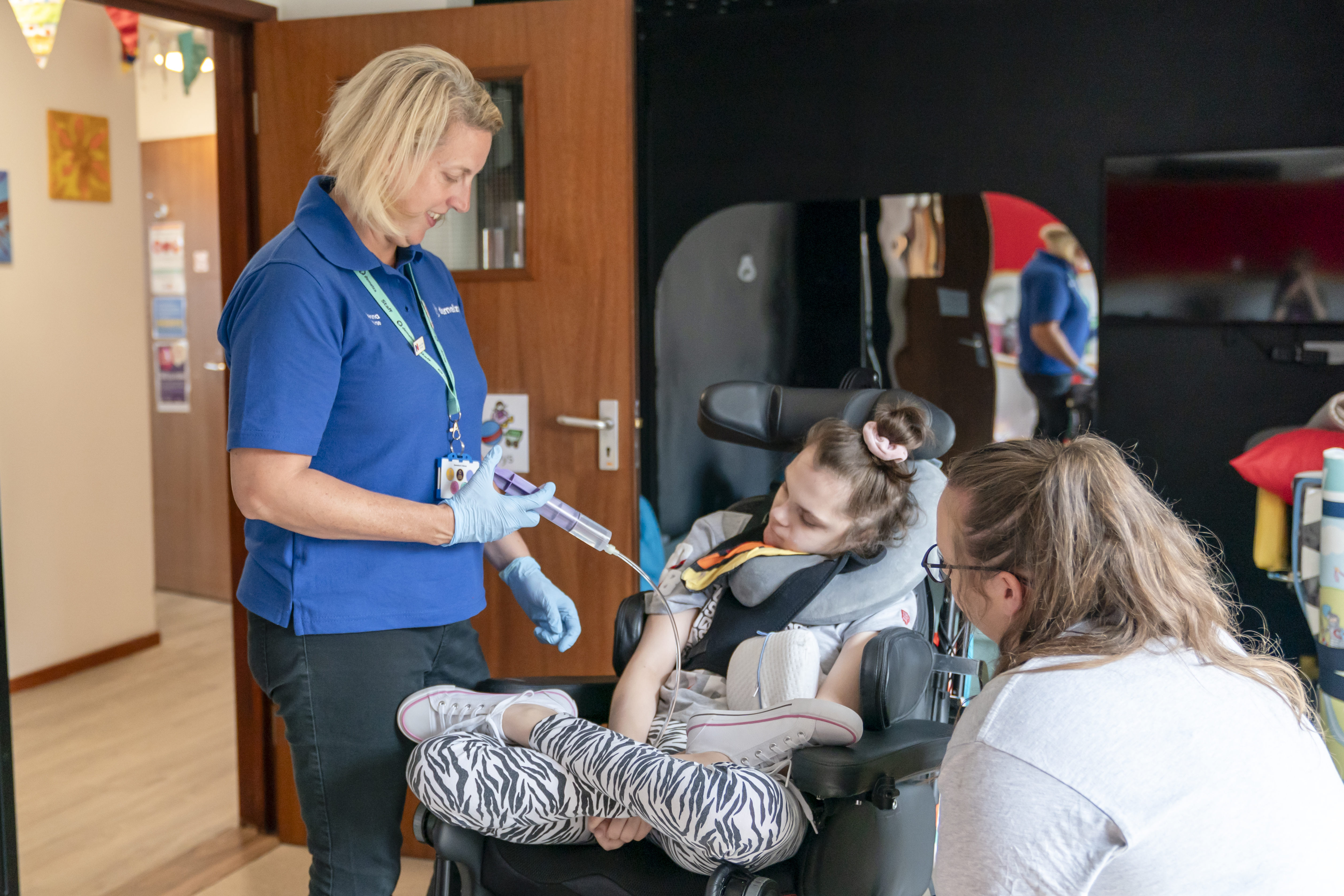 A blonde nurse providing care to a young person in a wheelchair at East Sussex