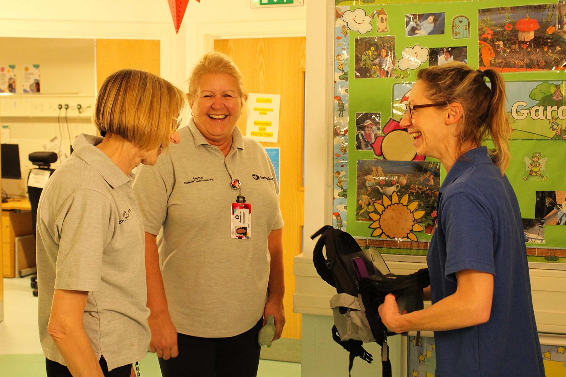 Three Nurses in Demelza clothing looking at each other and smiling in a hallway