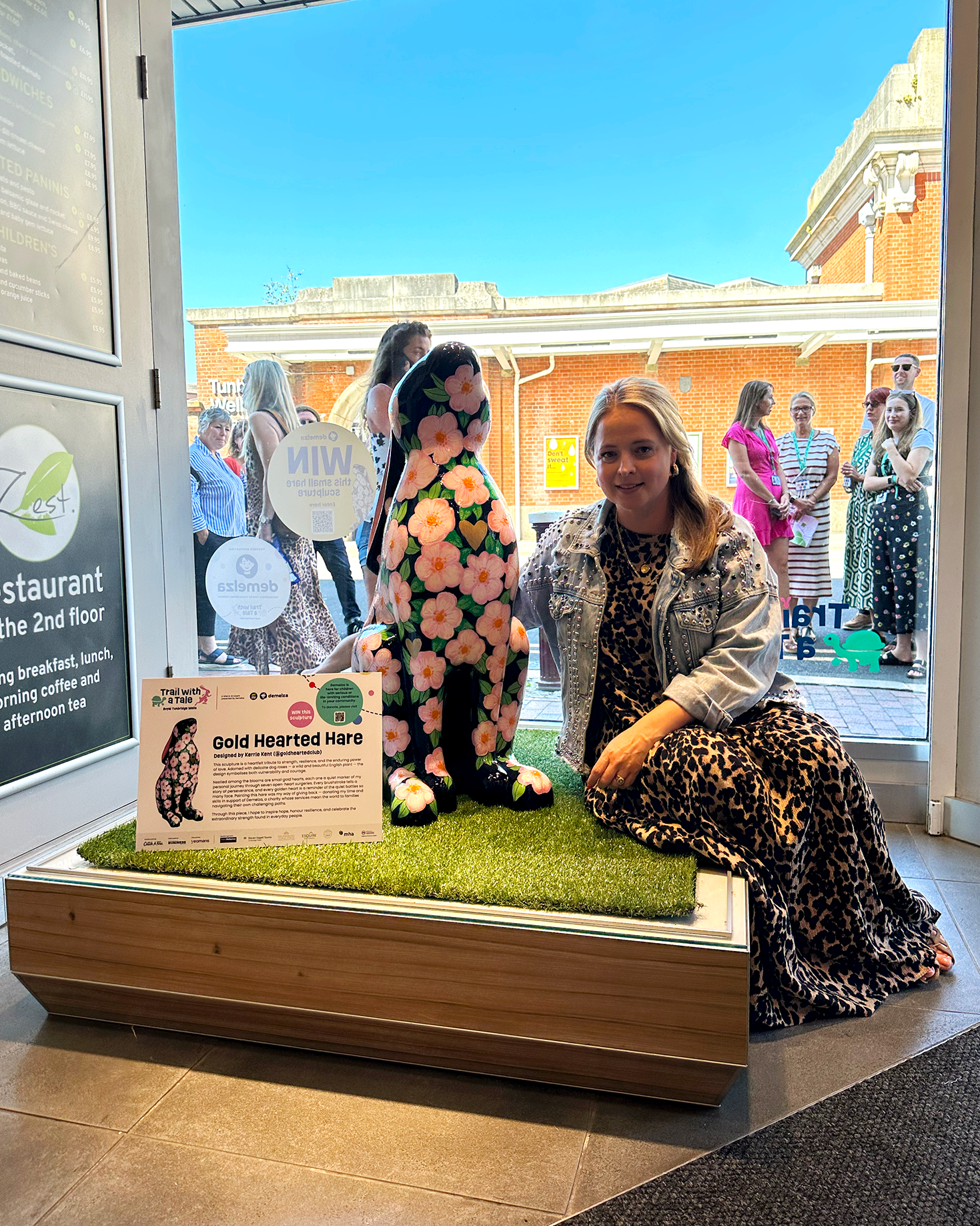 Image of artist Kerrie Kent sitting next to a sculpture she painted for Trail with a Tale