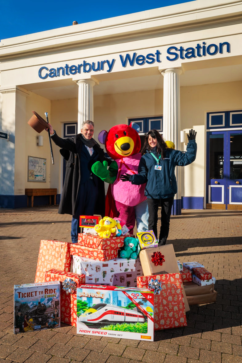 Two people standing outside Canterbury West train station with a stack of presents