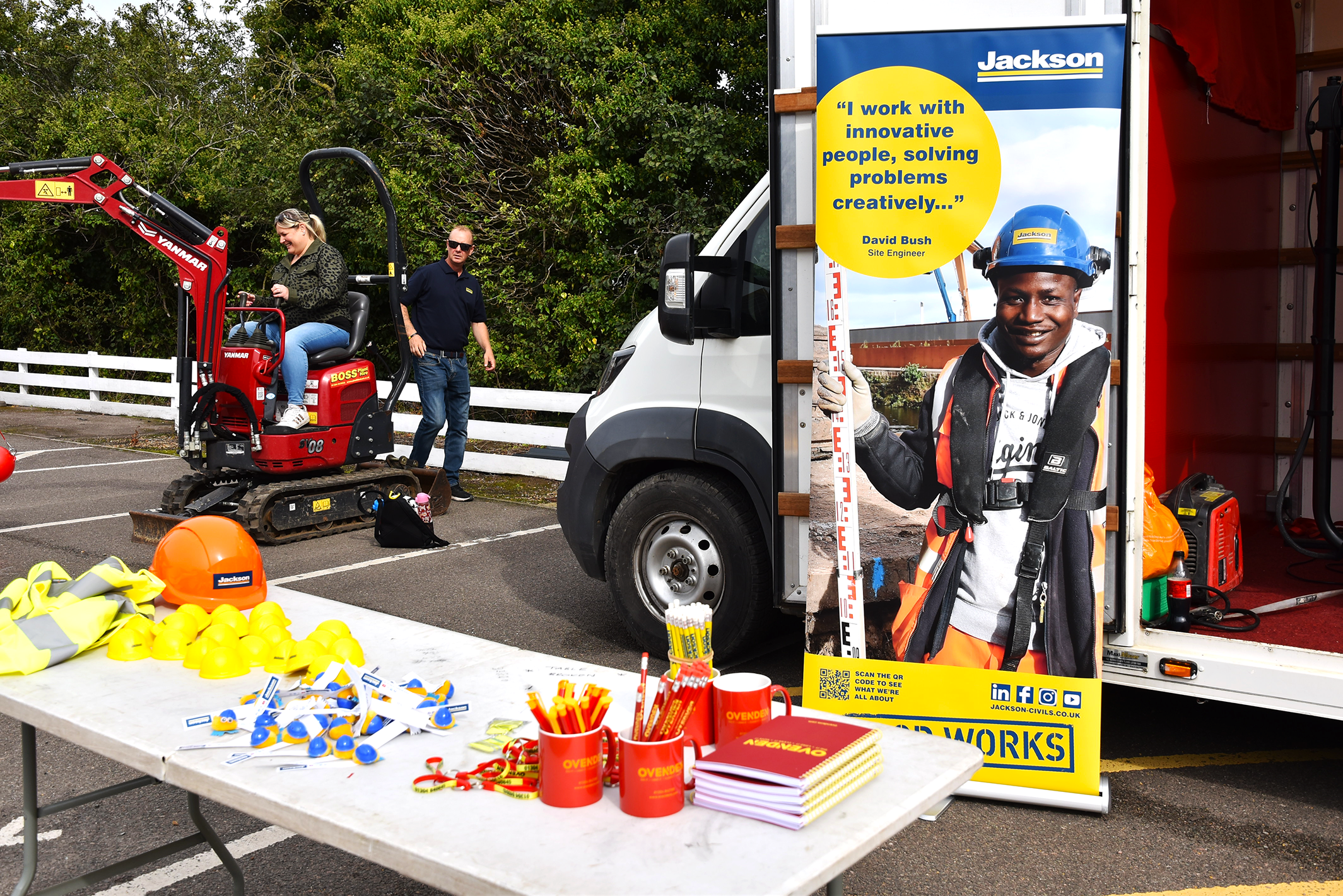A stall set up by Jackson Civil Engineering, table is full of different Jackson merchandise such as hard hats, pencils, and mugs