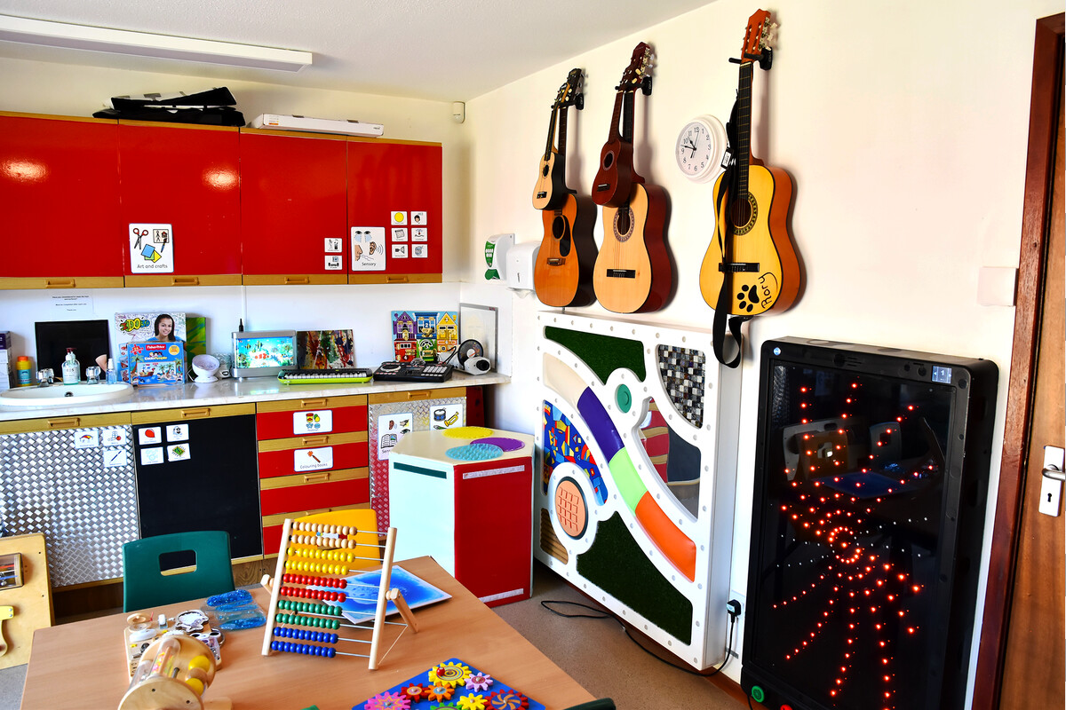 Brightly coloured East Sussex art room with guitars, musical and sensory equipment, art supplies, and toys for creative play.