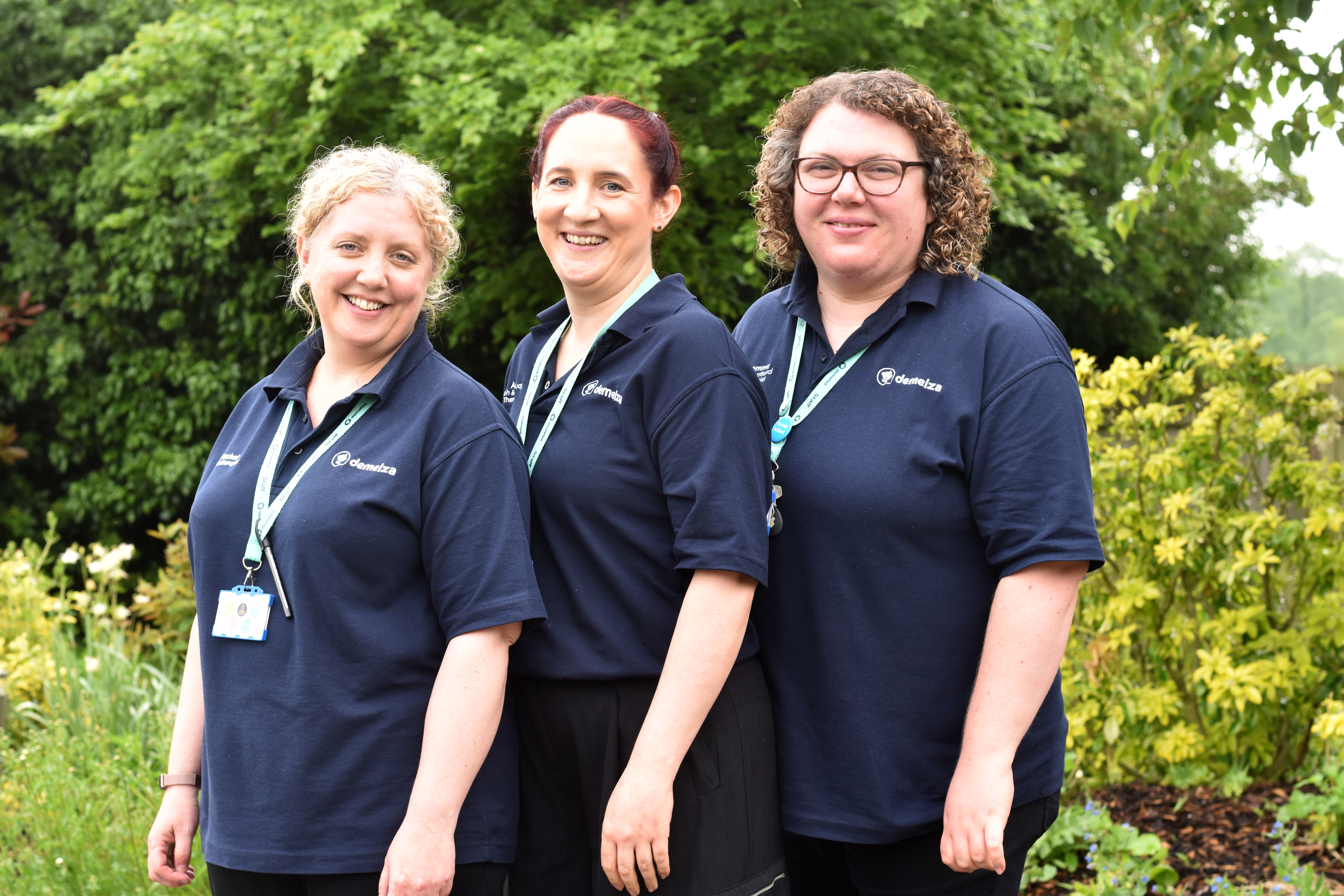 Three Demelza staff members standing up next to each other and smiling