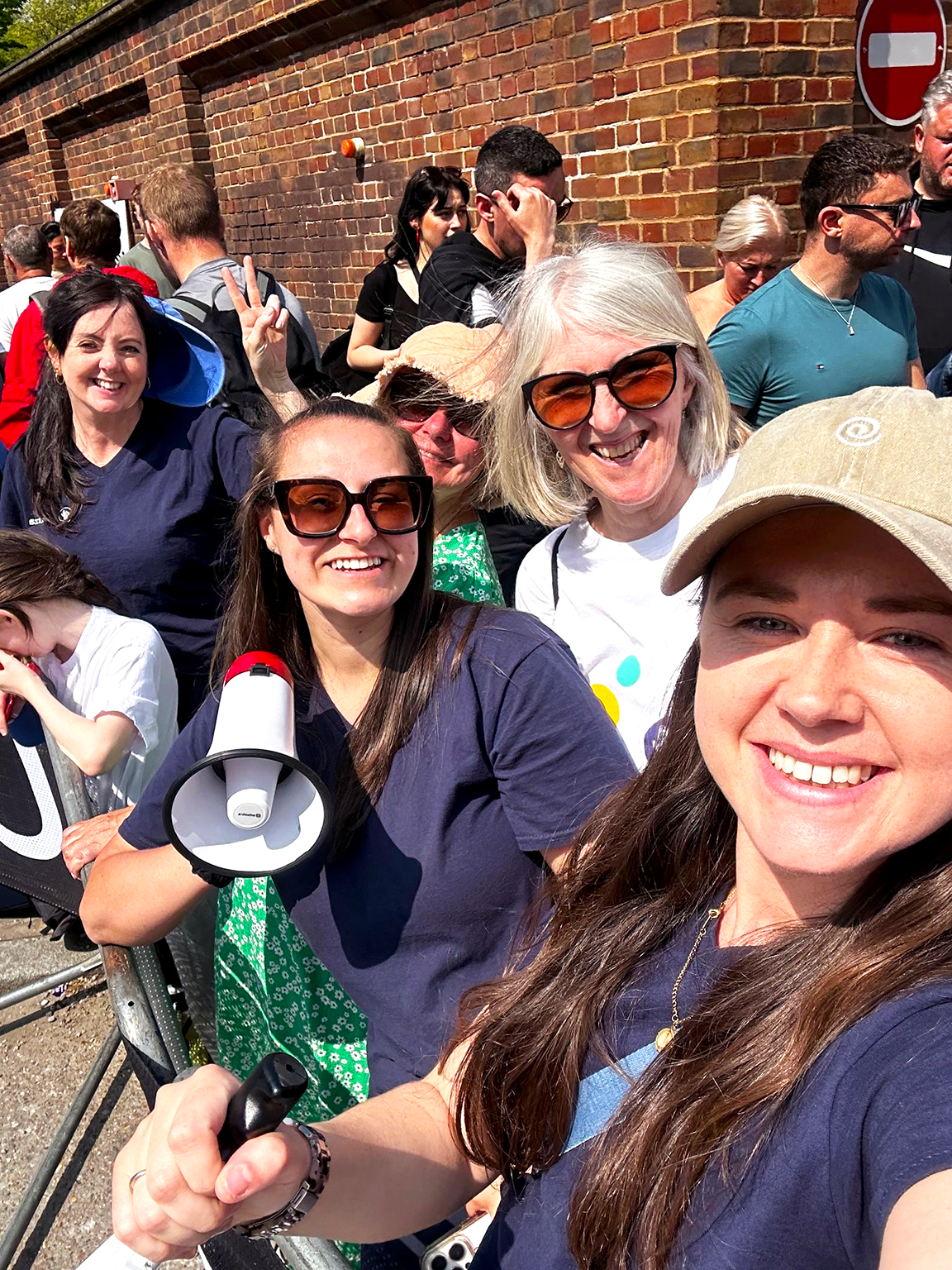 A group of five women smiling towards the camera in Demelza uniform who are out supporting runners at the London Marathon 2025