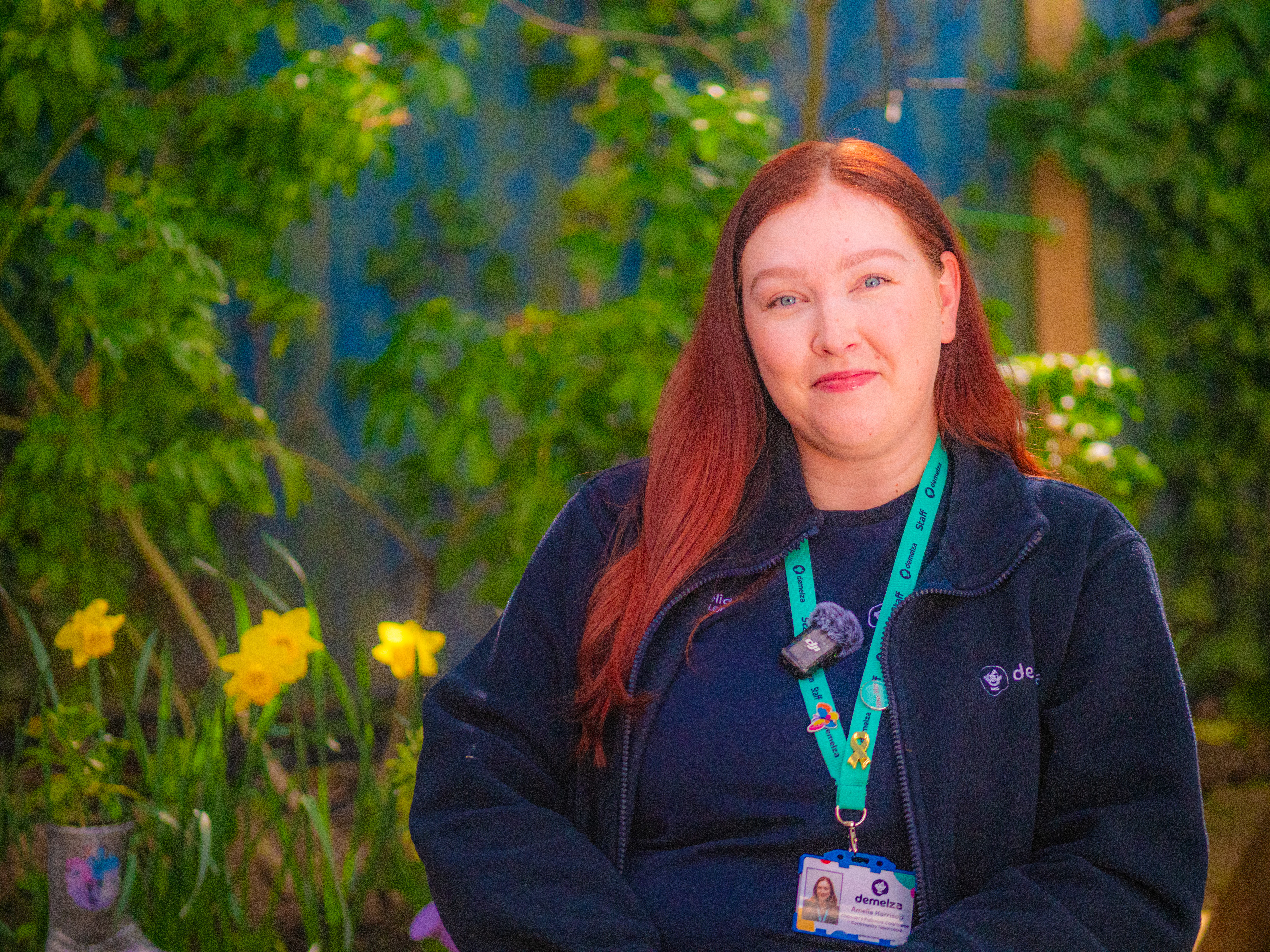 A nurse with ginger hair sitting down and smiling