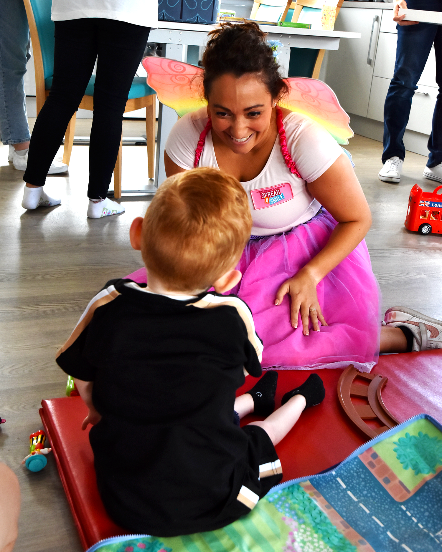 A child with ginger hair looking at a woman dressed as a fairy