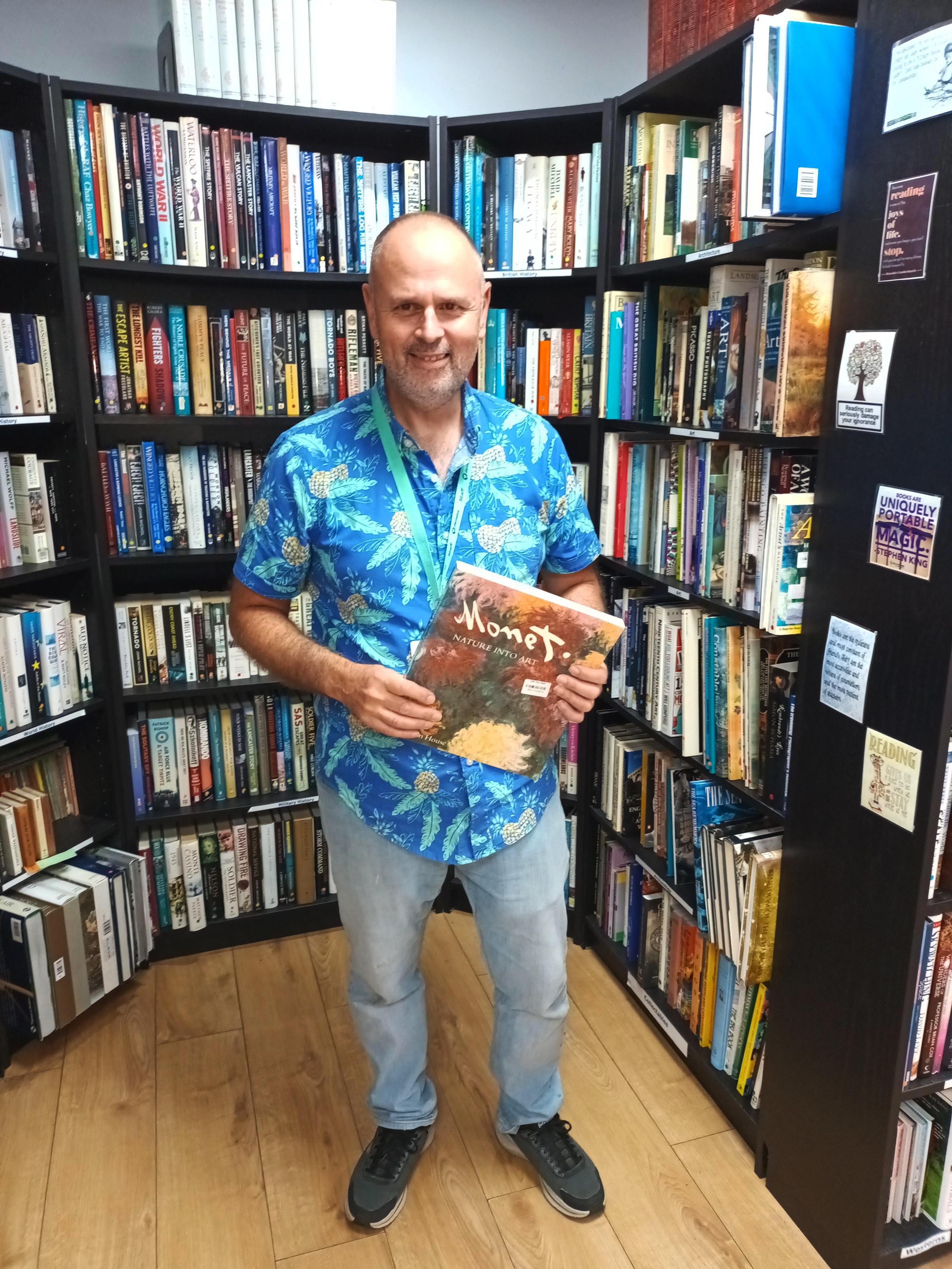 Image of volunteer holding up a book in a charity shop