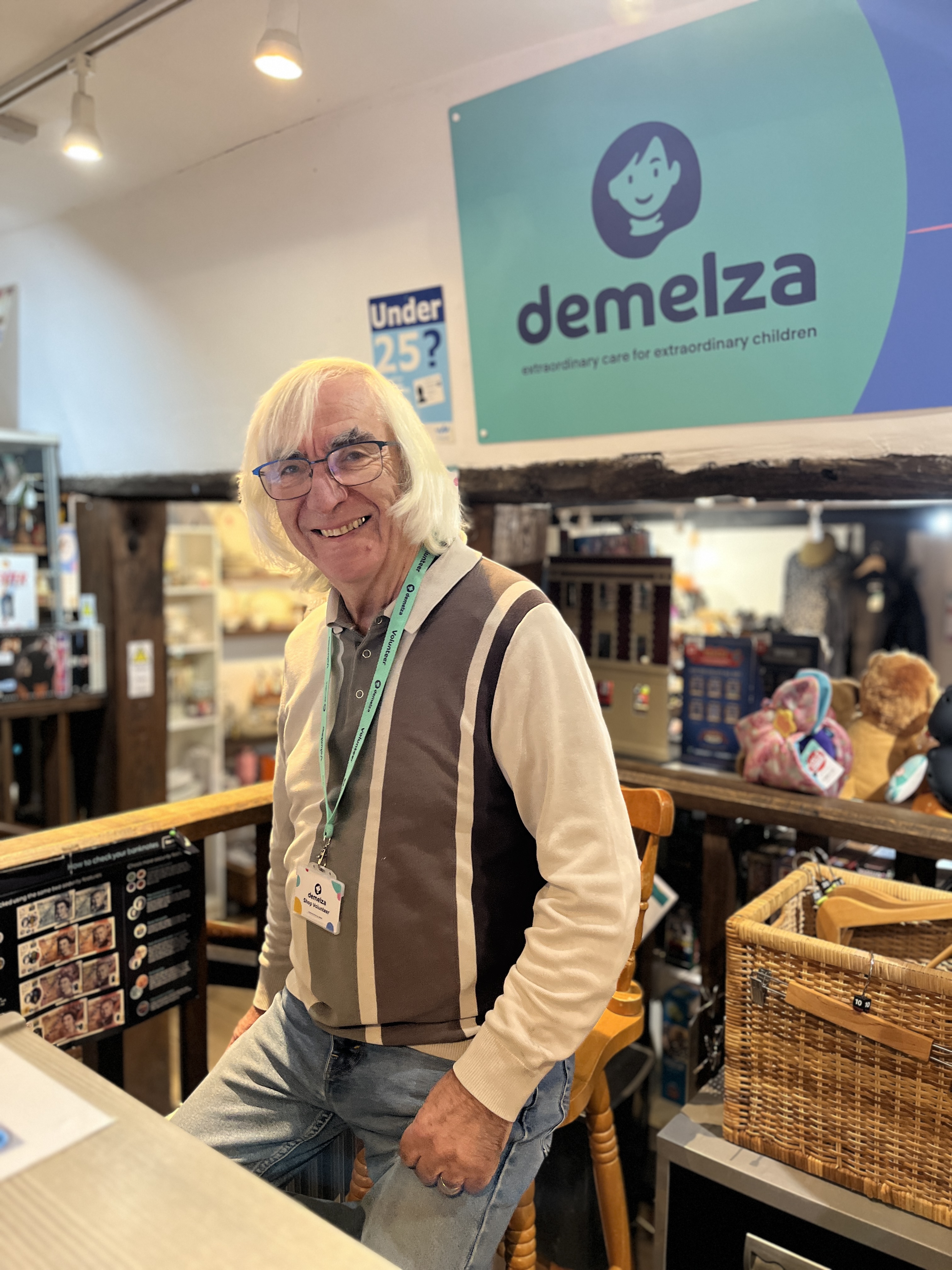 Volunteer Dave stands behind the till at the Tenterden shop, smiling warmly at customers.