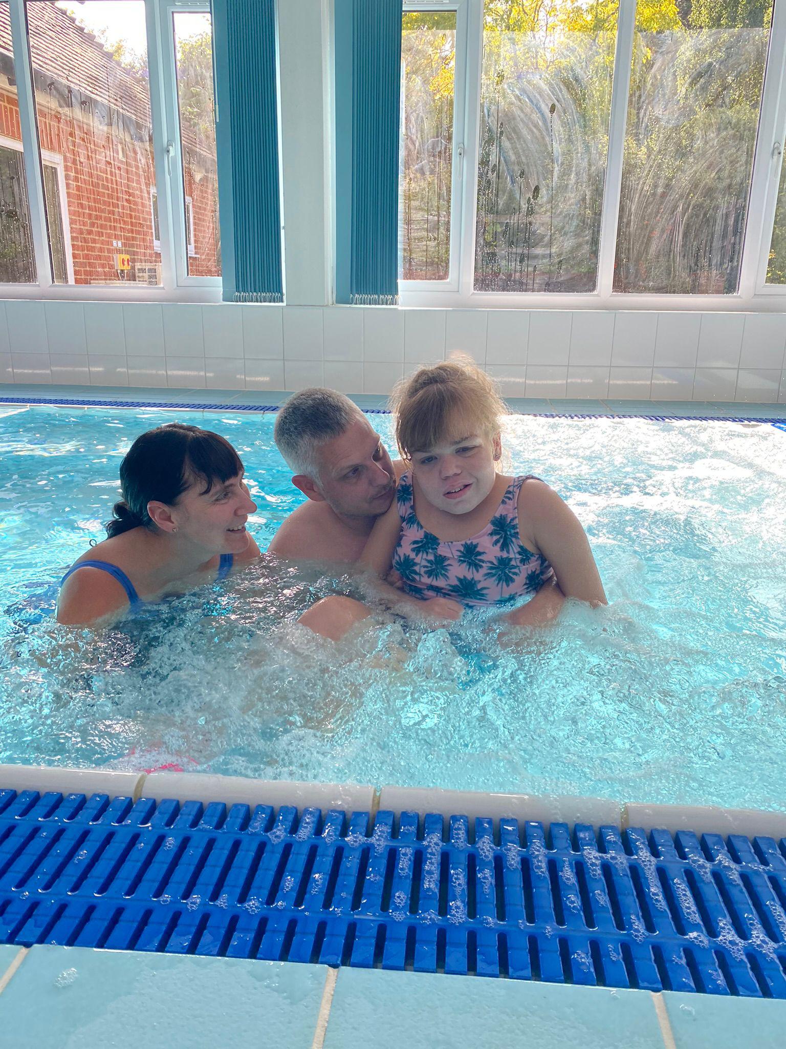 Young person in pool with family