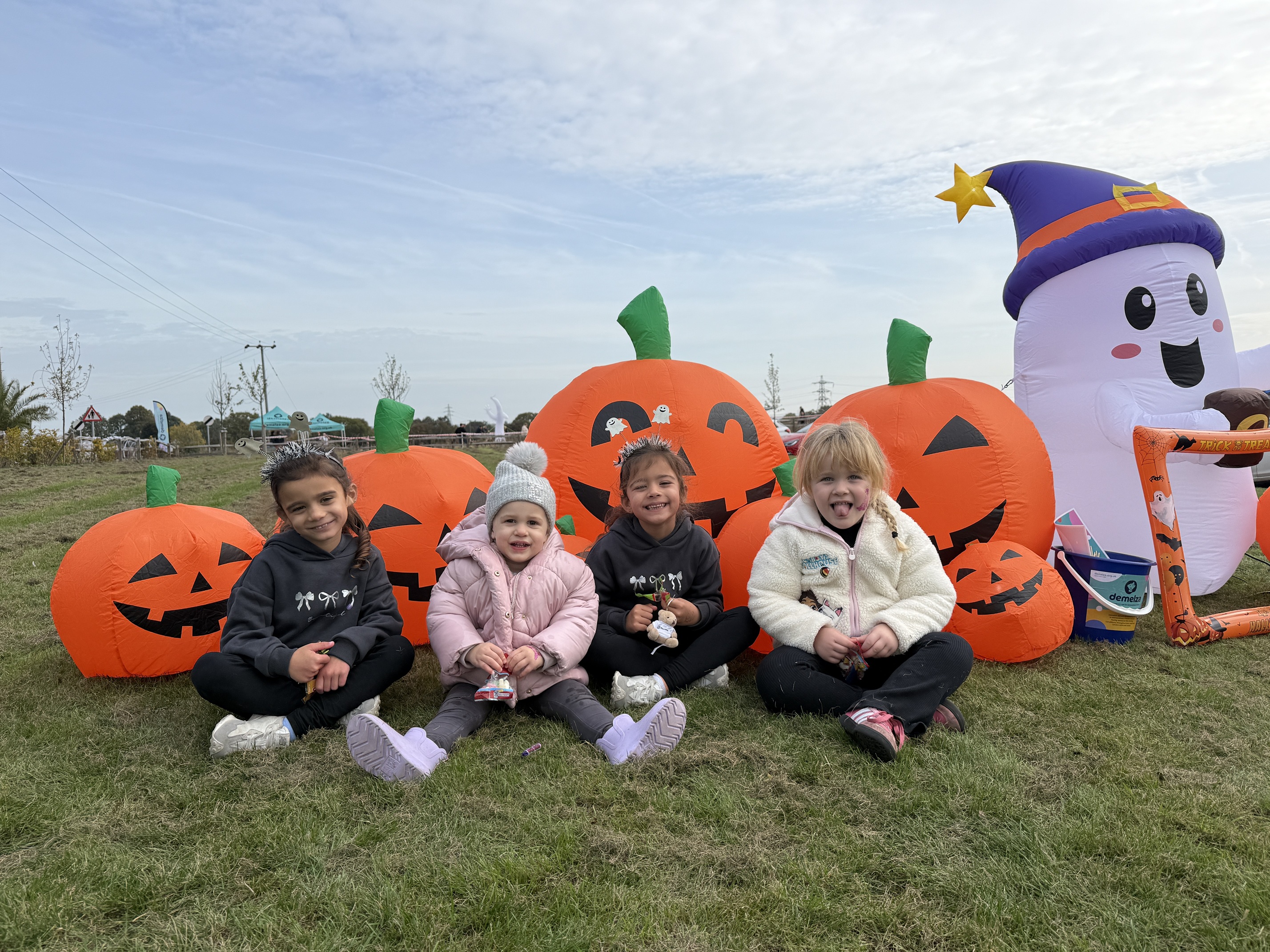 Four children sitting in front of inflatable pumpkins at the pumpkin patch