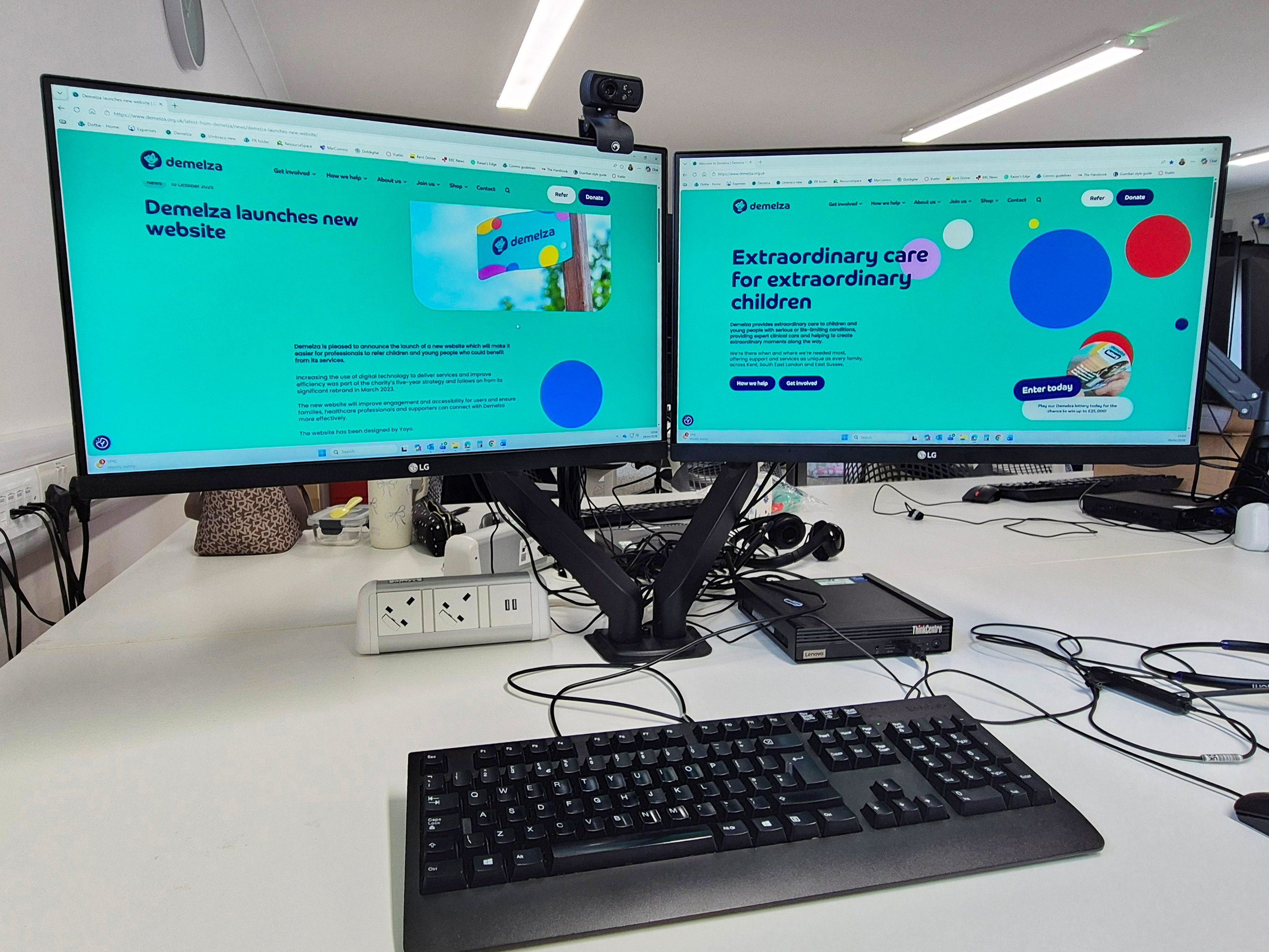 A desk with two monitors with Demelza's website displayed on the screens