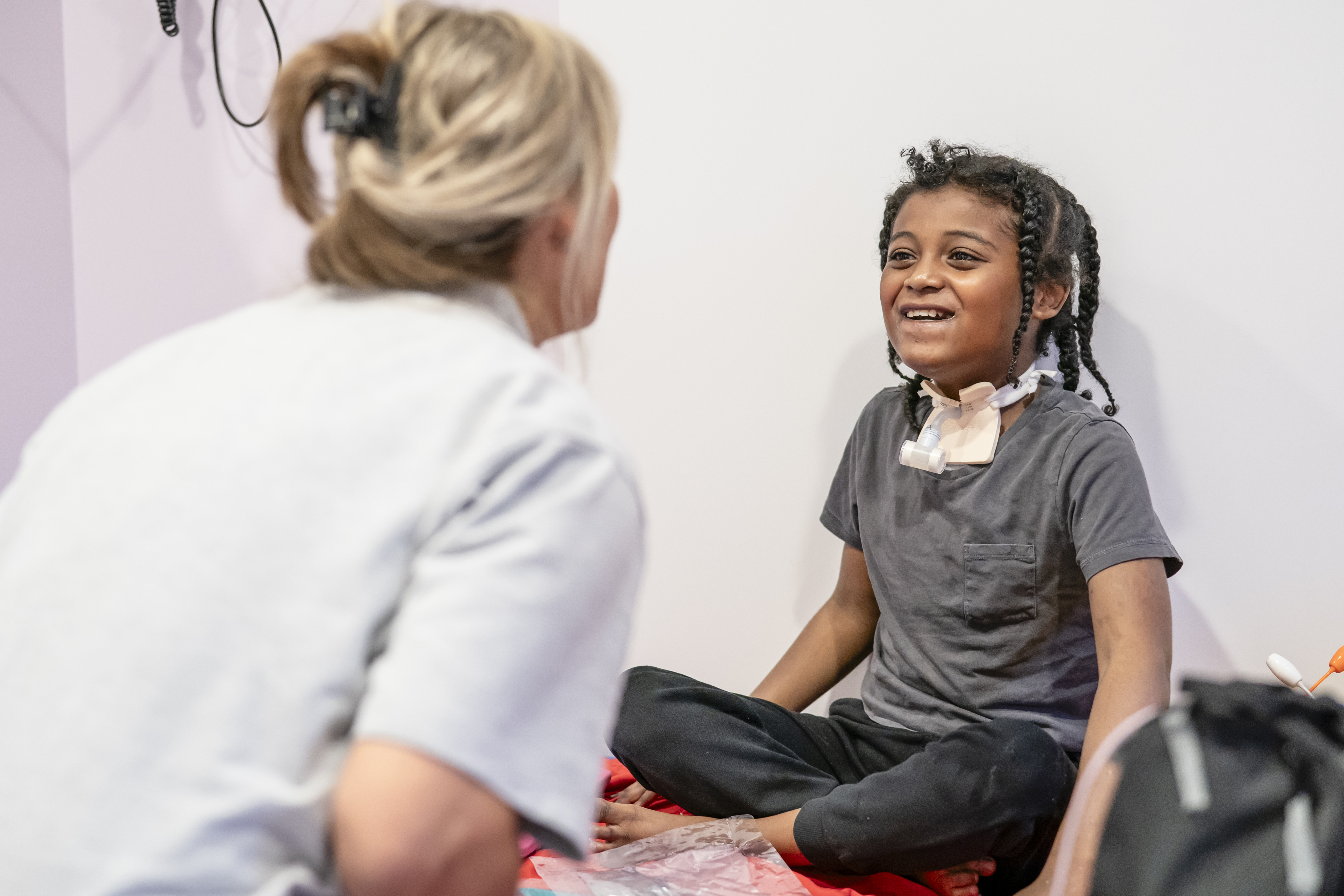 A female nurse playing with a child who is smiling back at her