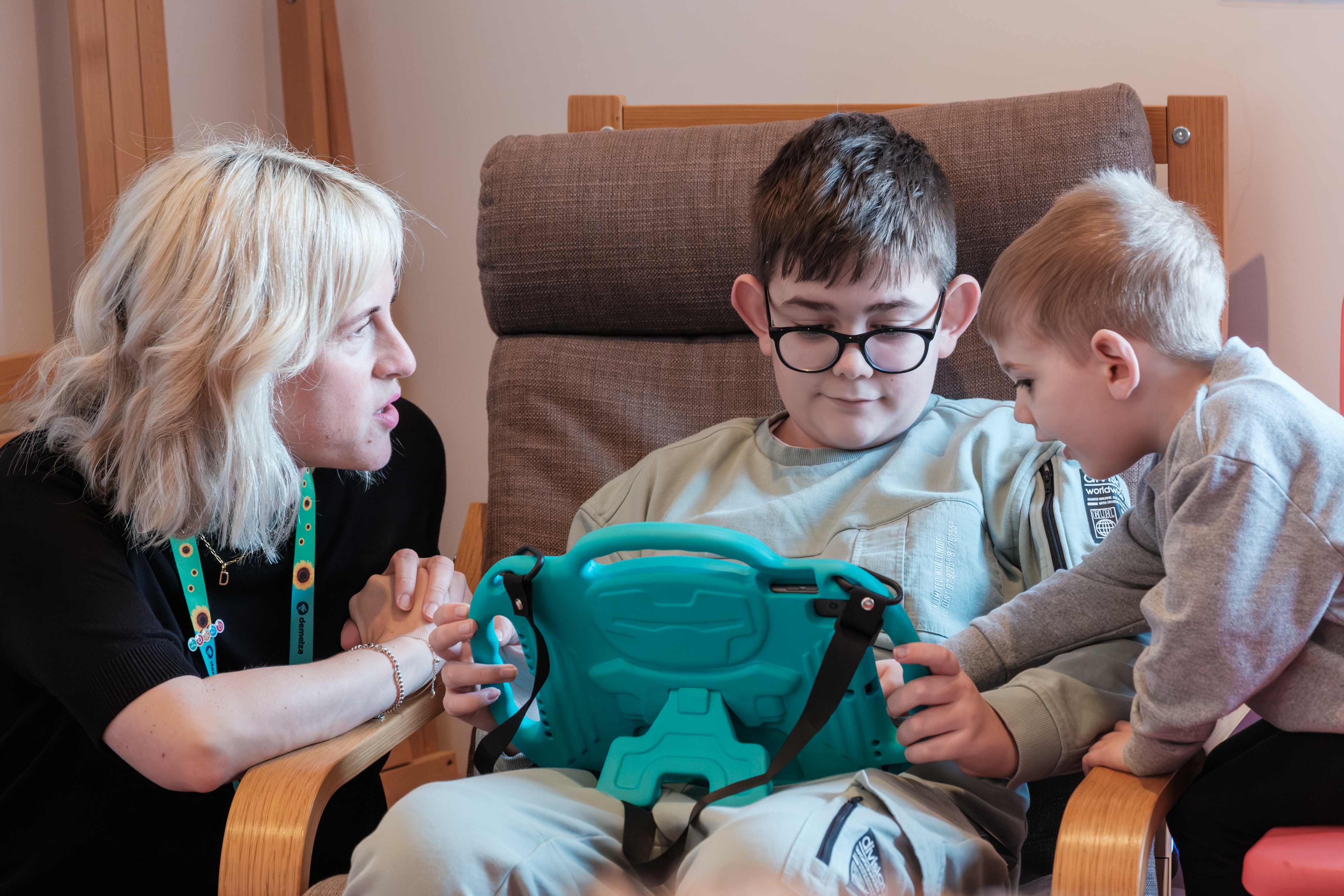 Two brothers with music therapist Kelly looking at a pad during a creative therapy session