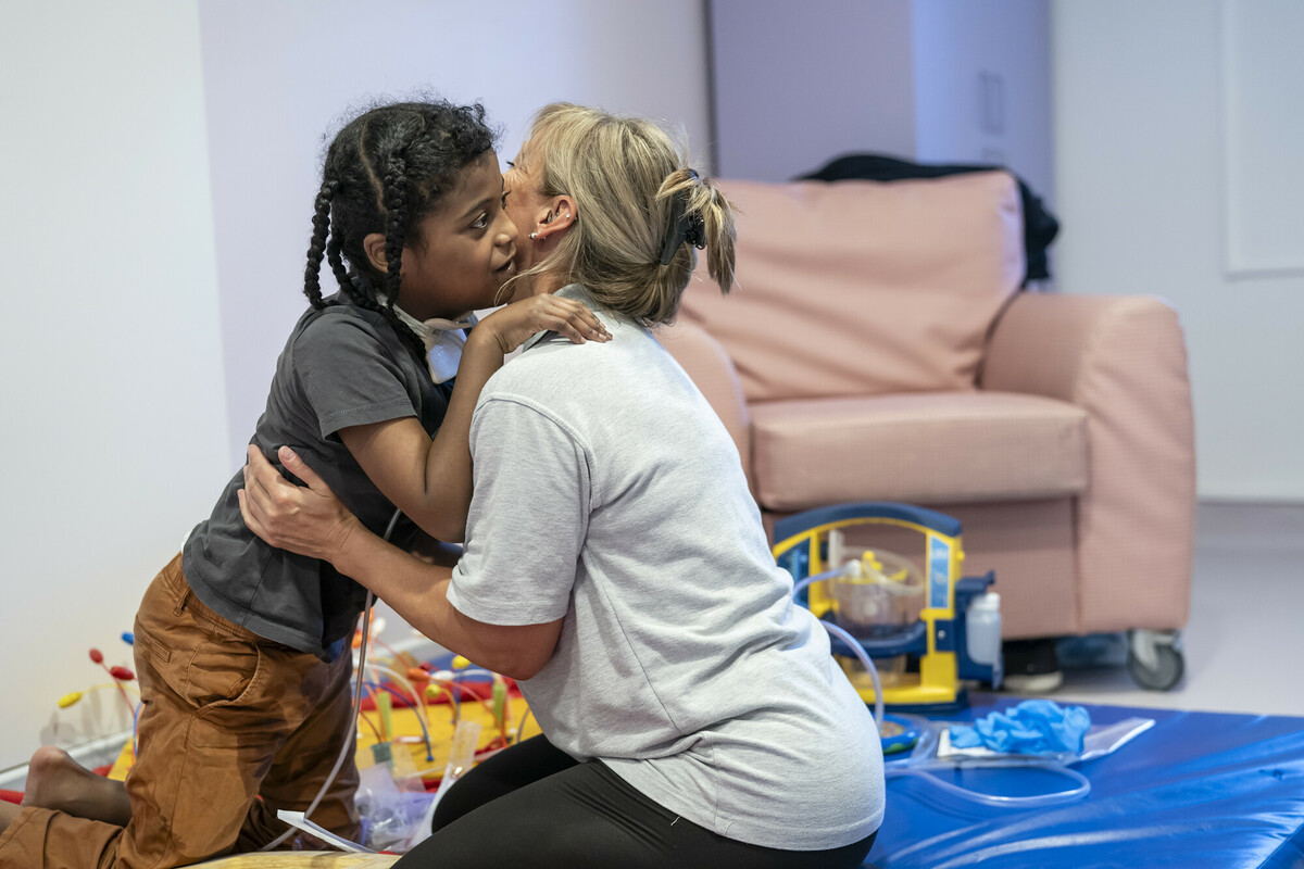 Ahmed and Jackie hugging while playing with toys on the lounge floor at Demelza South East London