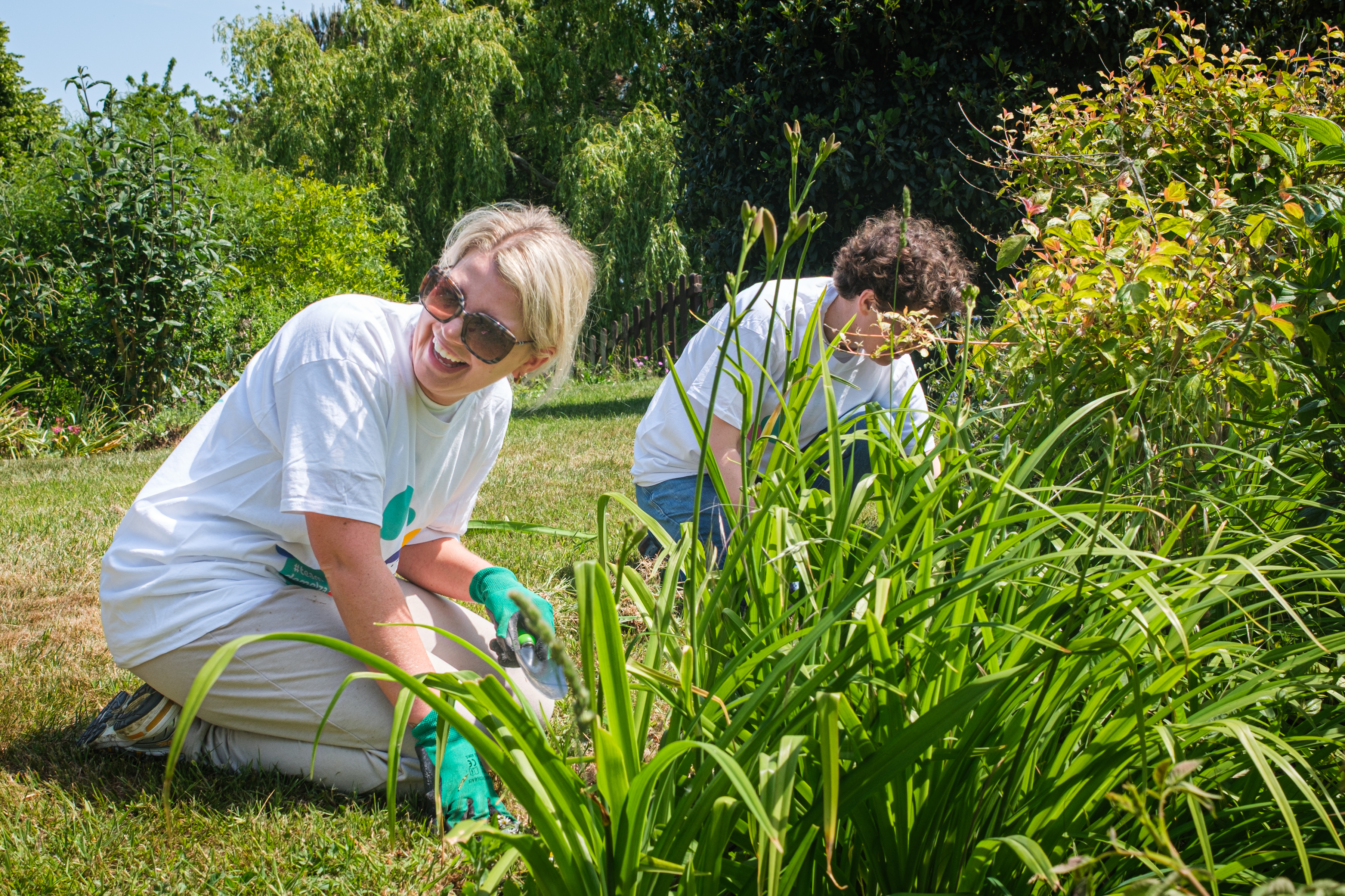 A woman with blonde hair and a young man with brown hair volunteering in the garden